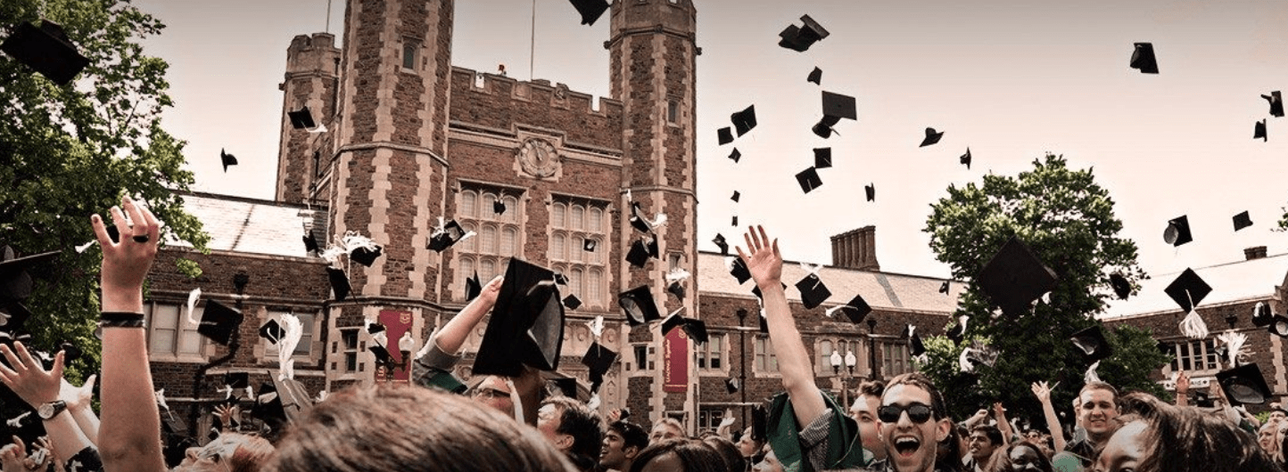 Graduating college students throw their caps at Commencement with a college gothic building in the background