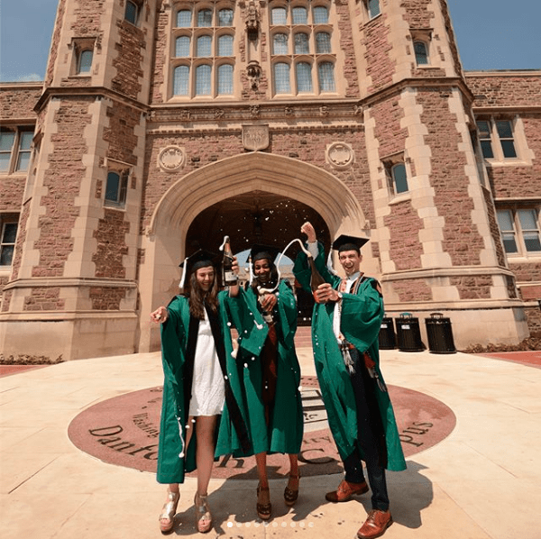 Three college graduates celebrate in front of Brookings Hall at Washington University in St. Louis