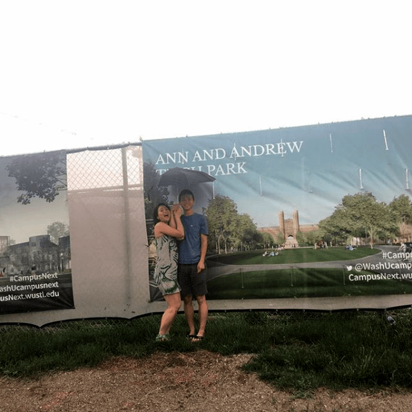 Two college students stand in front of a construction banner on the campus of Washington University in St. Louis