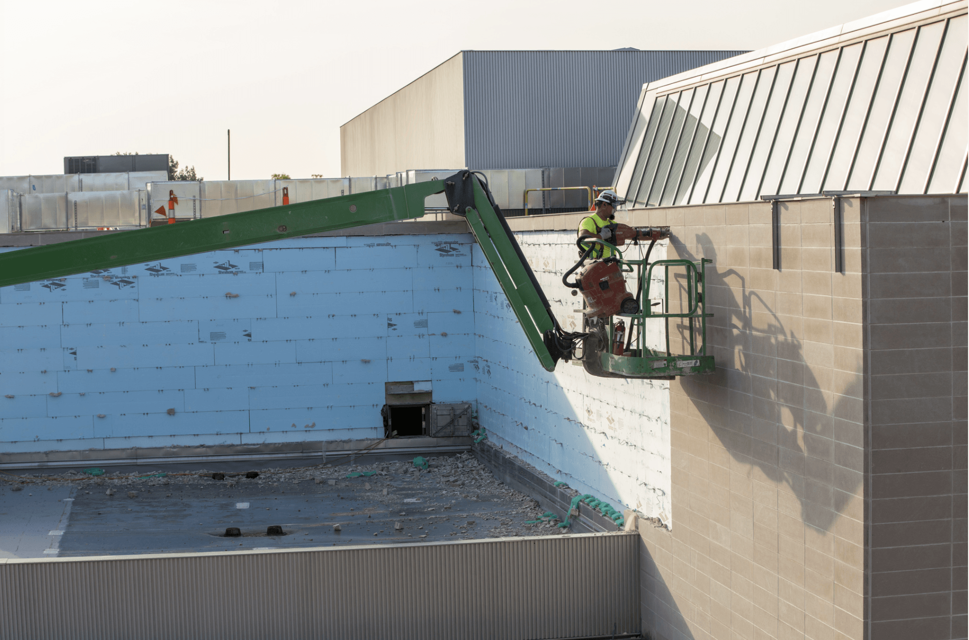 A construction worker on a scaffold does masonry work on the side of a building