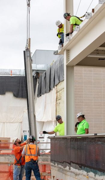 Workers install massive glass window panels on Weil Hall
