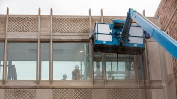 Workers test watertightness of windows on bridge between Jubel Hall and Whitaker Hall